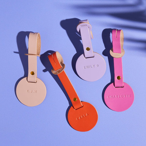 Four personalised luggage tags in pink, orange and lilac