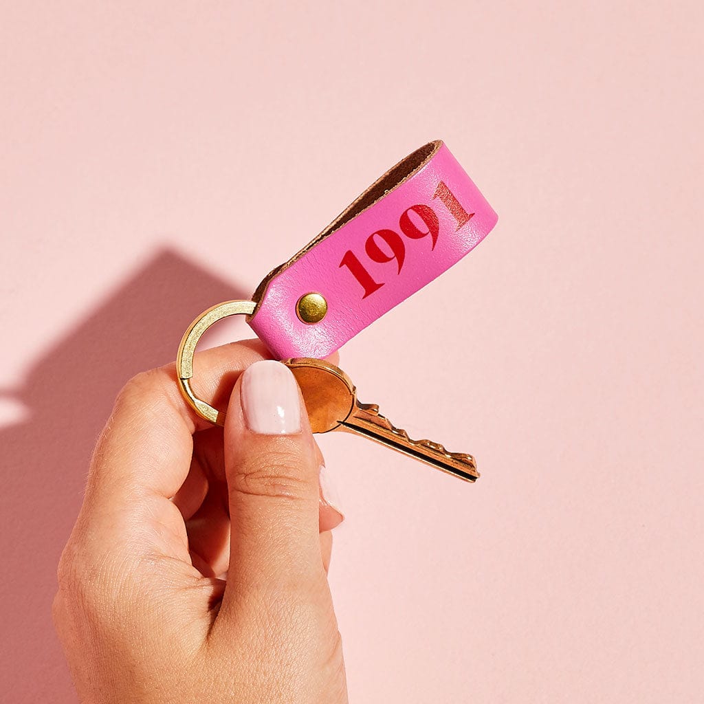 bright pink leather keyring printed with the year 1991, held in hand - by Sbri