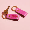 pair of bright pink leather keyrings by Sbri, personalised with initials and the year 1991
