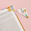 Lilac and white leather bookmarks with floral pattern and personalised names. The bookmark is shown on the corner of a page.